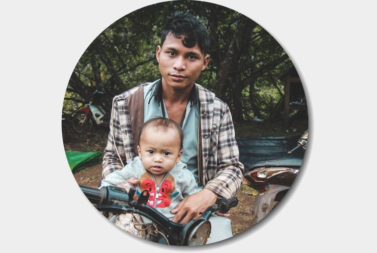 Young father sitting on motorbike with young child on his lap