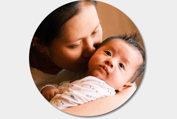 Close-up of young mother holding and kissing her baby's face