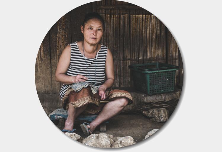 Lady sitting outside her home sewing
