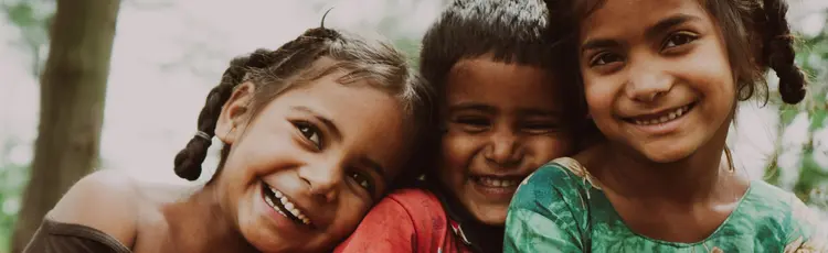 3 young children leaning on each other and smiling